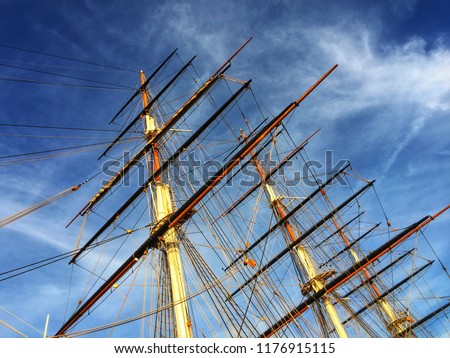 Looking up at an old sailing ship's mast and dramatic blue sky and clouds