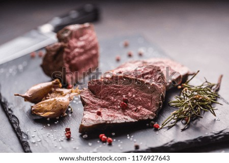 Juicy beef steak with spices and herbs on cutting board.
