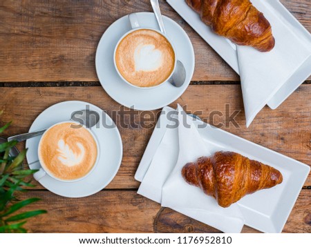 Coffee and croissant for breakfast. Cafe culture. Croissants with two small cups cappuccino with picture, top view