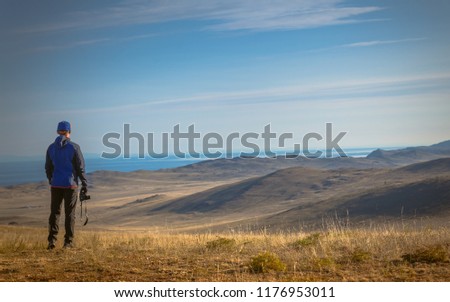 Man with a camera looks at autumn landscape