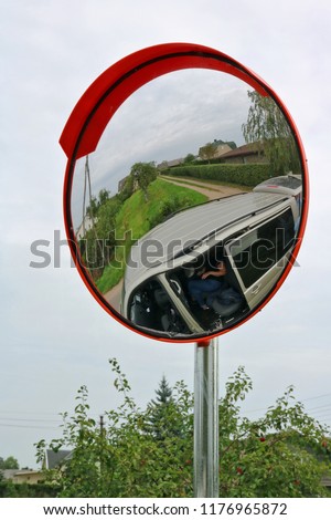 A round convex mirror is installed at the village crossroads for cars safety.Cloudy autumn  day  rural landscape