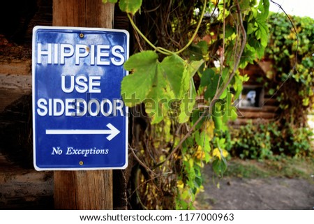 Hippies Use Sidedoor sign screwed into a wooden post on a log cabin