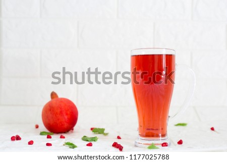 A big glass of pomegranate juice on wooden table with white brick background. Detox drink