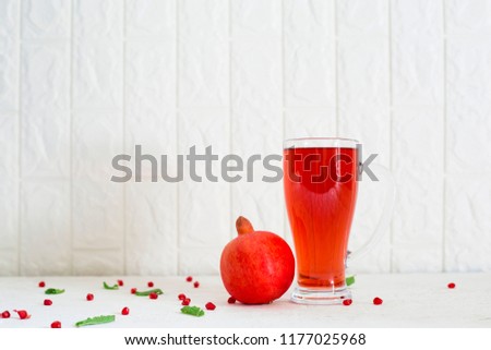 Whole pomegranate,seeds, mint leaves and Big Glass of pomegranate juice on white background