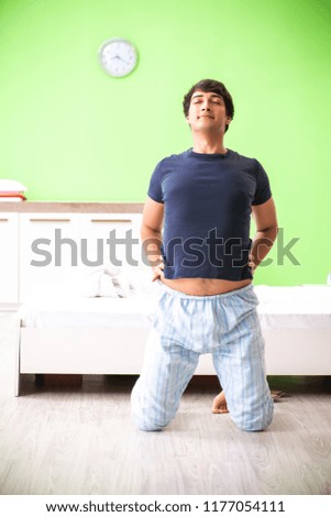 Young man in pajamas doing morning exercises 