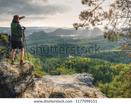 Photographer or videographer  traveler with heavy backpack and tripod in hand is preparing for art work. Artist in pure nature take impressive landscape photos.