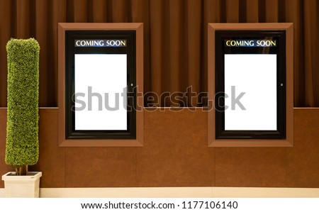 Empty isolated cinema poster panel on the wall of theater walkway, white blank mockup movie frame with coming soon text for insert design