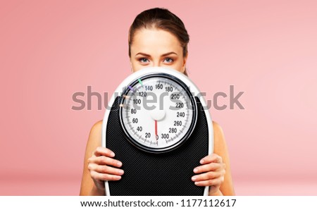 Beautiful young s woman holding scales Royalty-Free Stock Photo #1177112617
