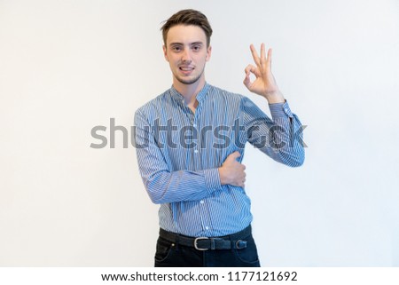 Positive confident young man showing ok sign and looking at camera. Content successful male entrepreneur in shirt gesturing hand as symbol of work done. Good job concept