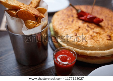 Golden potato wedges with big burger on the table in a restaurant