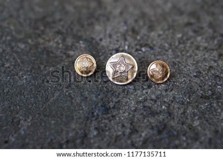 Old coat of arms of the Soviet Union on a military button. Star on the background of a concrete bunker. Historical photo