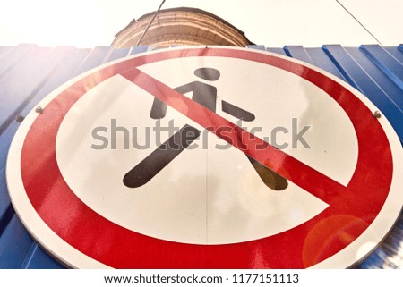 white with red lines and a man sign prohibiting the movement of people in a danger zone on a metal fence of blue color