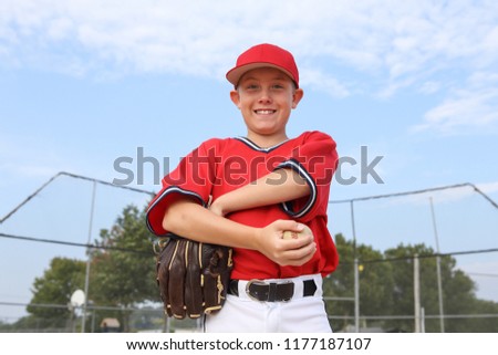 Boy pitcher smiling and holding a baseball