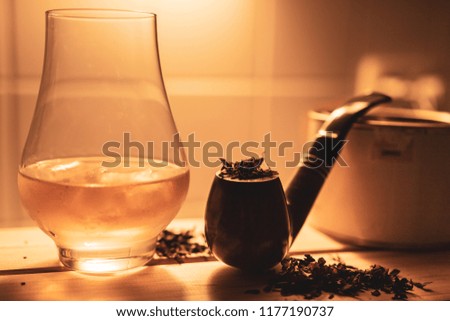Whiskey in nosing glass with smoking pipe and tabacco