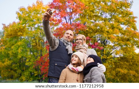 family, technology and people concept - happy mother, father, daughter and son taking selfie by camera over autumn park background