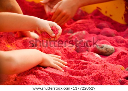 children play in a decorative red sand