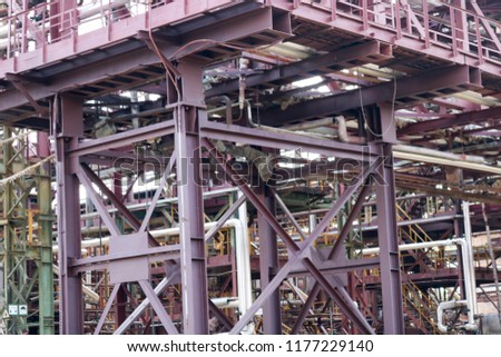 A large iron metal piping trestle with pipes and electric wires and equipment at the petrochemical refinery industrial refinery.