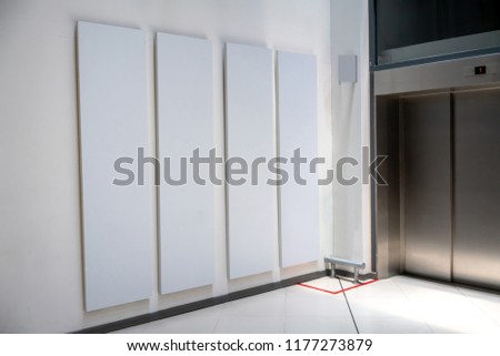 Four big vertical poster on white background in front of elevator