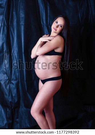 young pregnant woman with long hair on black background, lifesty
