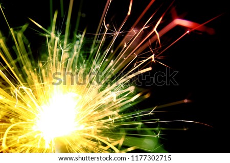 Sparkler background / A sparkler is a type of hand held firework that burns slowly while emitting colored flames, sparks, and other effects