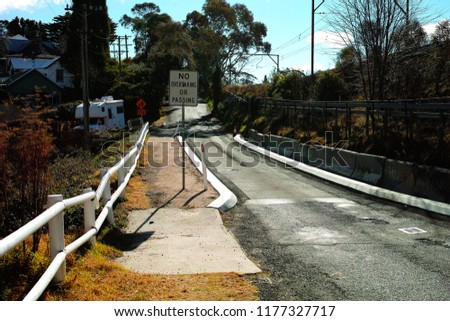 Narrow fenced bridge on a suburban road with traffic sign. Village street in Leura, Blue Mountains, Australia.
