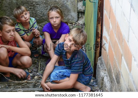 Children in the basement, three boys and a girl near the iron door are hiding on the steps from the outside world. Post-production photo.