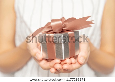 Closeup of woman hands holding a small gift box for special event. Christmas, birthday or new year concept.