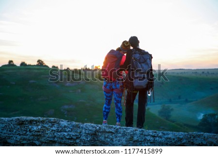Photo from back of hugging couple of tourists on mountain