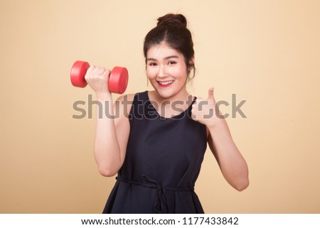 Healthy Asian woman thumbs up with dumbbells  on beige background