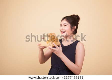 Young Asian woman open a gift box  on beige background