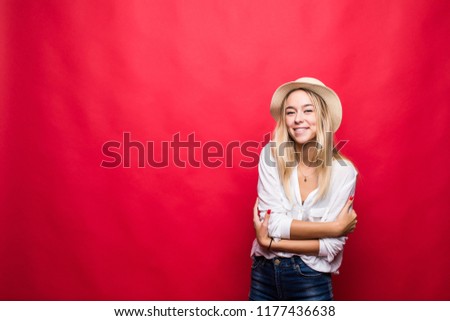 Young woman wearing in straw hat with crossed hands smiling isolated on red background