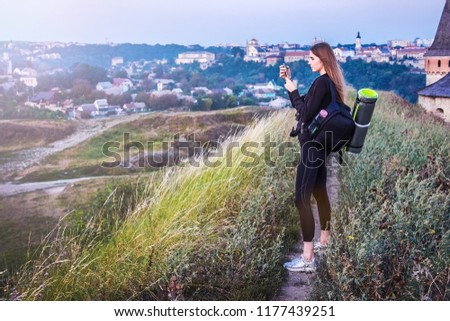 A young woman taking a picture of the city from her hotel room