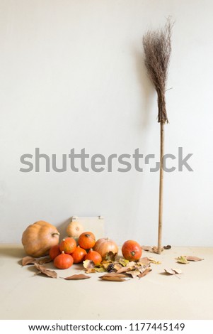 Halloween concept. Pumpkins, broom on white wall background