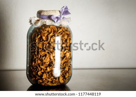 homemade canned dried apples in big glass jar stand on kitchen table against gray wall background