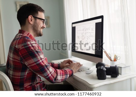 Young handsome designer working on project on computer