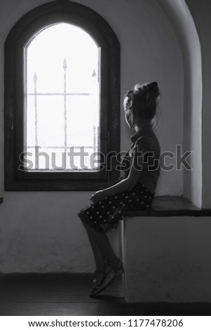 The girl sits in the castle by the window.