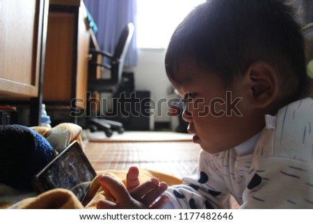 
A small boy is watching cartoons in a cell phone in low light
