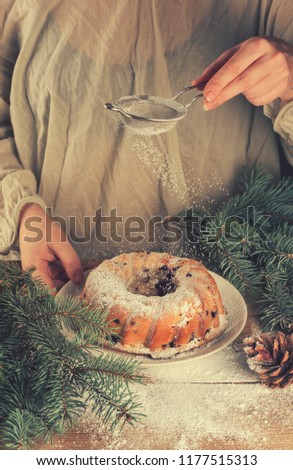 Christmas cupcake and women's hands sprinkling it with powdered sugar
