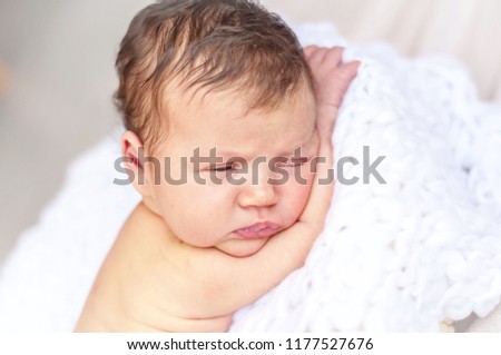 A funny sleepy newborn baby stock image. Cute infant falling asleep, about to sleep. Several weeks old baby, just born.