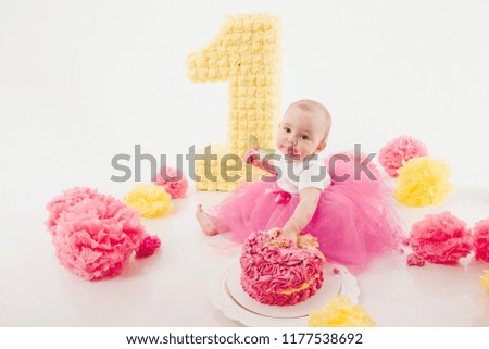 a little girl eats cake with her hands. The baby was covered in food. isolated white background. birthday party