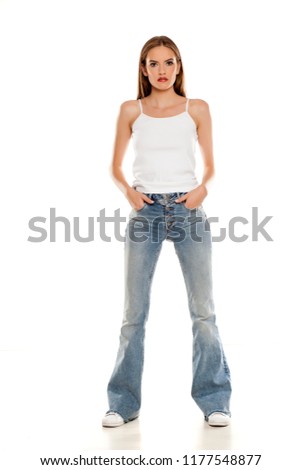young pretty woman posing in bell bottom jeans on white background