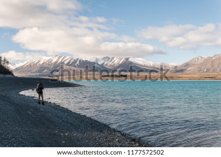 Man taking a photo of mountains at Lake Tekapo