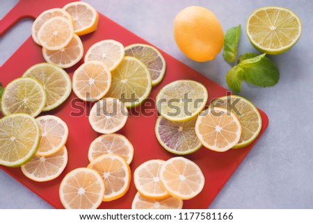 Slices of lemon and lime and mint leaves on red