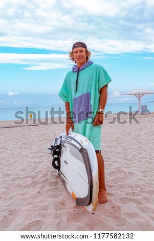 Handsome man walk with white blank surfing board wait for wave to surf spot at sea ocean shore. View from side. Concept of sport, fitness, freedom, happiness, new modern life, hipster.