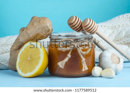 Garlic, a honey jar, ginger, lemon and honey spoons on a blue background. Maintenance of immunity. Treatment of colds and flu. Products for immunity. Immunity concept.  
