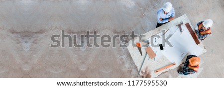 Team of young man and woman engineer and architects working, meeting, discussing,designing, planing, measuring layout of building blueprints in construction site floor at factory.top view & copy space Royalty-Free Stock Photo #1177595530