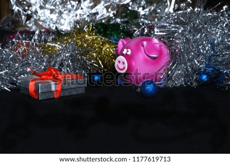 Congratulations on a new year, a candle, a tinsel, a pig, on a black background.
