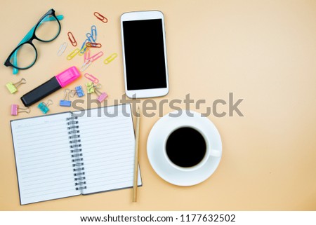 Notebook mobile phone calculator and black coffee white cup blue glasses on orange background pastel style with copyspace flatlay