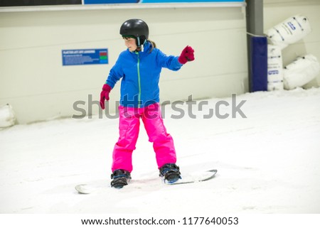 young girl riding snowbord at indoor snow center