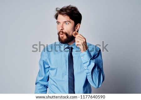 bearded man in blue shirt holds Bitcoin in hand                               